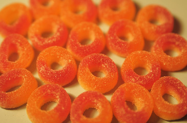 Orange jelly candies on yellow background.