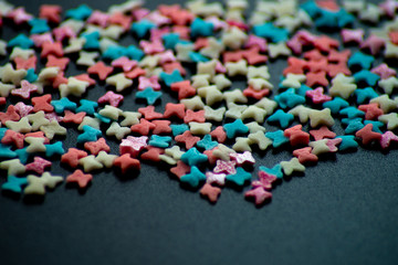 multicolored confectionery sprinkle in the form of butterflies on a black background