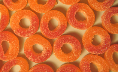 Orange jelly candies on yellow background.