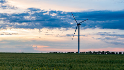 wind generator in grass field at sunset