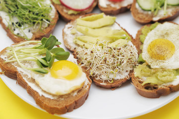 Sandwiches with healthy vegetables, tomatoes, eggs, micro greens on plate on colorful background. Healthy food concept.