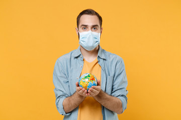 Young man in sterile face mask posing isolated on yellow background studio portrait. Epidemic...