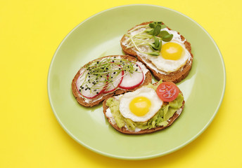  Sandwiches with healthy vegetables, tomatoes, eggs, micro greens on plate on colorful background. Healthy food concept.