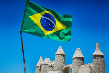 A sand castle on Copacabana Beach in Rio de Janeiro, Brazil, with the Brazilian flag flying above.