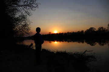 a child at sunset by the river enjoys nature and fresh air, a breath of clean air during quarantine