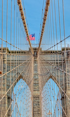Fototapeta na wymiar The United States flag on center of Brooklyn Bridge in New York, Vertically oriented shot