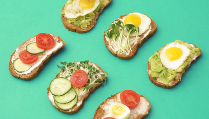  Sandwiches with healthy vegetables, tomatoes, eggs, micro greens on plate on colorful background. Healthy food concept.