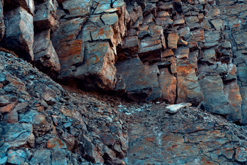 Natural basalt rock with cracks and crevices with a red color coming from iron. Rock wall texture....