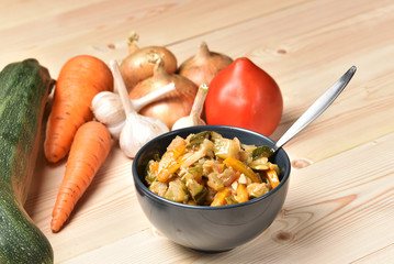 Vegetable saute on a wooden table surrounded by vegetables