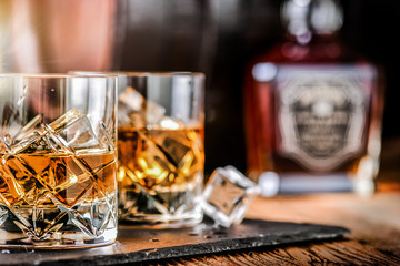 Glass of whiskey with ice cubes on black stone table. Side view with copy space alcohol concept.