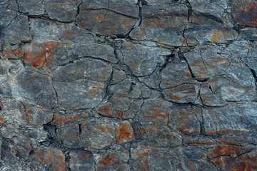 Natural basalt rock wall with cracks and crevices. Rock texture. Graphite stone wall. Stone...