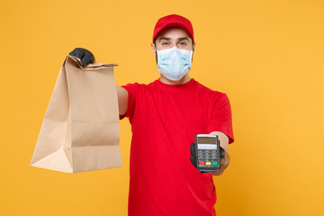 Delivery man employee in red cap blank t-shirt uniform mask glove hold craft paper packet terminal...