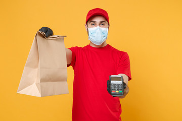 Delivery man employee in red cap blank t-shirt uniform mask glove hold craft paper packet terminal...