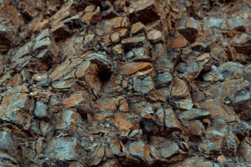 Natural basalt rock with cracks and crevices with a red color coming from iron. Rock wall texture. Graphite stone wall. Stone background. Photography made wit natural daylight. Texture designated for 