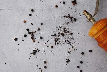 Old Wooden Pepper Mill with Peppercorns on a gray background. Top view.