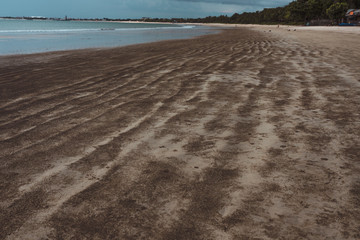 Deserted beach on the island of Bali. Clouds and clouds with rain of dark blue color. Sandy beach with sea and ocean. Tropical view. Hurricane.