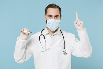 Male doctor man in gown face mask gloves isolated on blue background. Epidemic pandemic coronavirus 2019-ncov sars covid-19 flu virus concept. Hold blood test result Sample tube point index finger up.