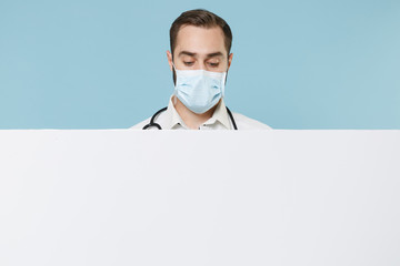 Male doctor man in gown sterile face mask isolated on blue background. Epidemic pandemic...