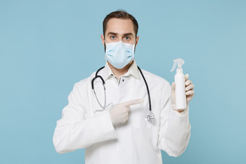 Doctor man in gown face mask gloves isolated on blue background. Epidemic pandemic coronavirus 2019-ncov sars covid-19 flu virus. Pointing finger on bottle with alcohol liquid antibacterial sanitizer.