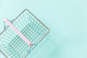 Small empty supermarket grocery shopping basket toy isolated on blue pastel colorful trendy background. Copy space. Sale buy mall market shop online shopping consumer concept.