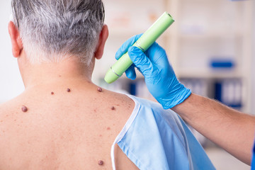 Old man visiting young male doctor dermatologist