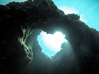 Low angle view of heart shape rock formation in sea - Powered by Adobe