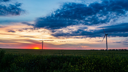Obraz premium wind generator in grass field at sunset