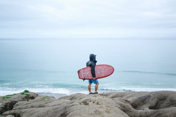 Fototapeta na wymiar Man with surfboard standing on rock