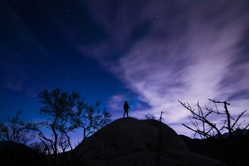 Man stargazing while standing on hilltop
