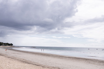 Deserted beach on the island of Bali. Clouds and clouds with rain of dark blue color. Sandy beach with sea and ocean. Tropical view. Hurricane.