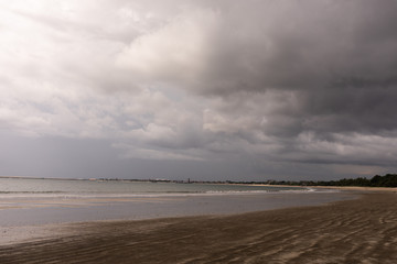 Deserted beach on the island of Bali. Clouds and clouds with rain of dark blue color. Sandy beach with sea and ocean. Tropical view. Hurricane.