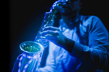 Saxophone musician playing the saxophone in a disco with a sax with led lights.