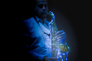 Saxophone musician playing the saxophone in a disco with a sax with led lights.