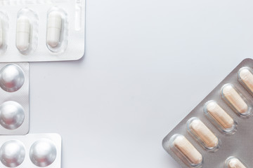 frame , macro closeup of pills and white capsules, on a silver pharmaceutical blister pack on a white background