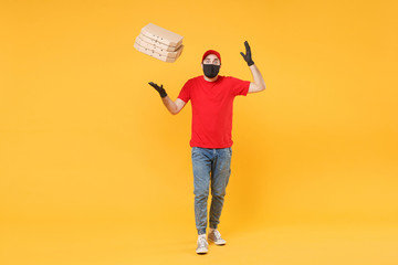 Delivery man employee in red cap t-shirt uniform black mask gloves give food order pizza boxes isolated on yellow background studio. Service quarantine pandemic coronavirus virus flu 2019-ncov concept