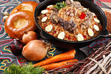 Flat lay of Uzbek PILAF. Traditional Uzbek setup with plov dish in centre decorated with bread, vegetables. Middle asian concept
