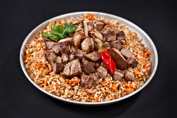 Plate of pilaf. Traditional Uzbek cuisine. Dish with meat, vegetables, garlic and chilli pepper. High quality. Ramadan Kareem