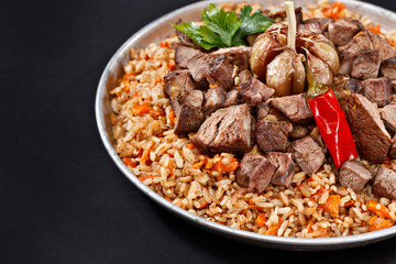Close-up plate of pilaf. Traditional Uzbek cuisine. Dish with meat, vegetables, garlic and chilli pepper. High quality. Ramadan Kareem