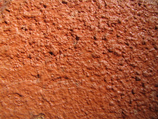 Dark light bright pastel orange red old paint background on rustic surface, natural plaster cement texture in concrete, stuccoed on facade wall in the sun.