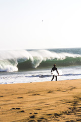 Rear view of man with surfboard walking on Newport Beach