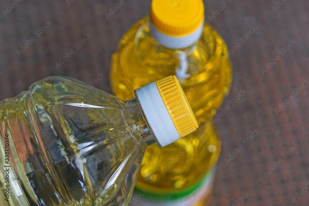 Wall mural two closed full plastic bottles with yellow sunflower oil on a brown table