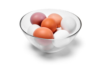 eggs of different colors from white to brown in a glass bowl, isolated on a white background