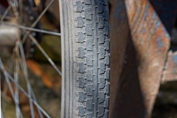 part of a wheel made of black rubber tire and gray metal spokes on a brown background