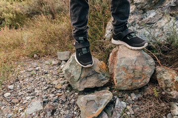 children's feet in sneakers on stones in the mountains