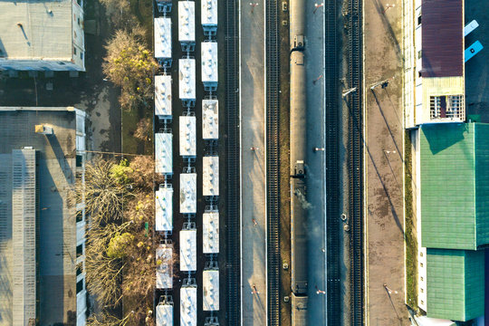 Top down aerial view of many cargo train cars on railway tracks.
