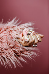 Naklejka na ściany i meble hand of a young woman crushed a pink cake with cream in a pink fur coat on a pink background