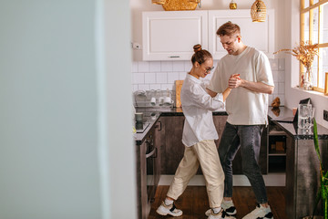 happy young caucasian married couple enjoy dancing at home in the kitchen, enjoy spending time together at weekends. couple in love, feelings, free time