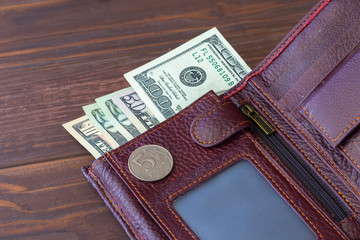 Cinnamon wallet. It has five rubles and next to it are banknotes of one hundred dollars. Foreign...