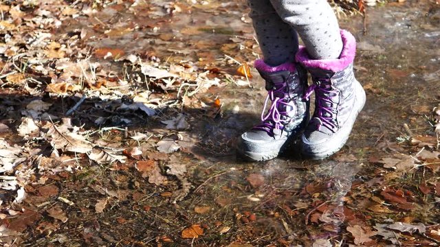 F&uuml;&szlig;e eines Kindes laufen vorsichtig auf einer d&uuml;nnen Eisfl&auml;che
