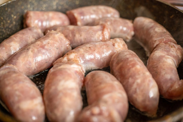 Raw sausages are fried in a pan close up